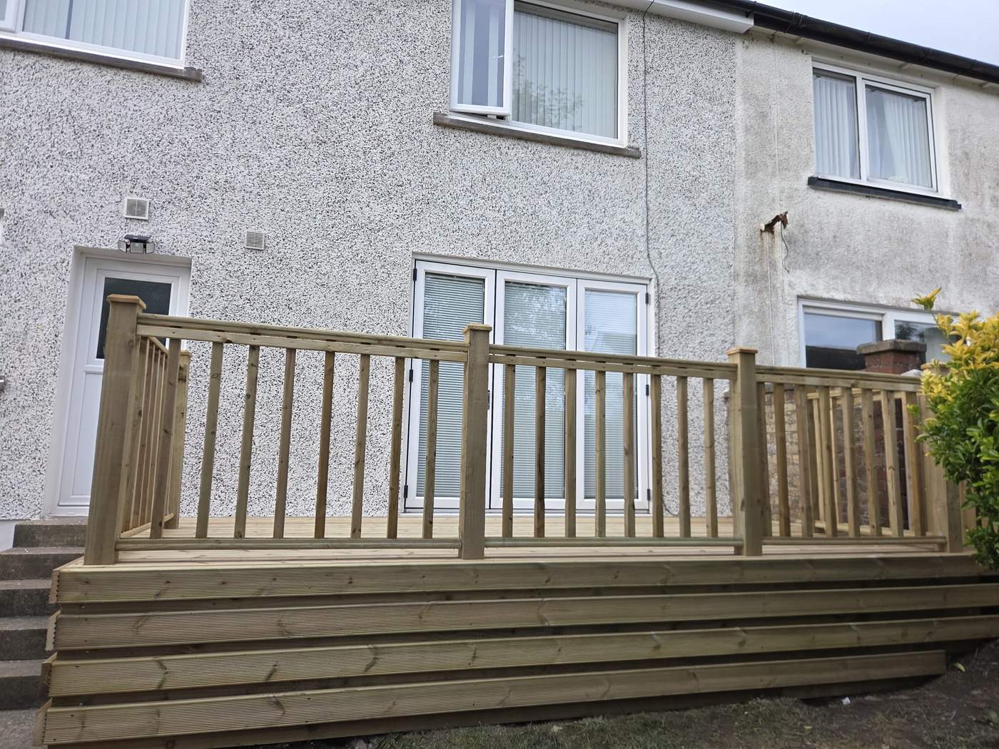Timber deck and spindle balustrade running the full width of the back of a house