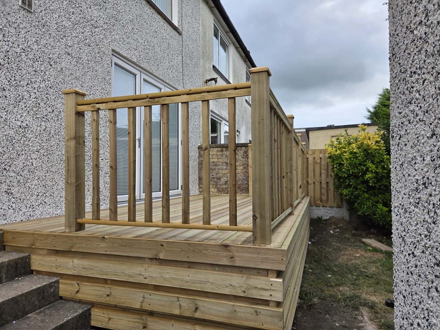 Raised timber deck with a spindle balustrade and boxed-in edge beside garden steps