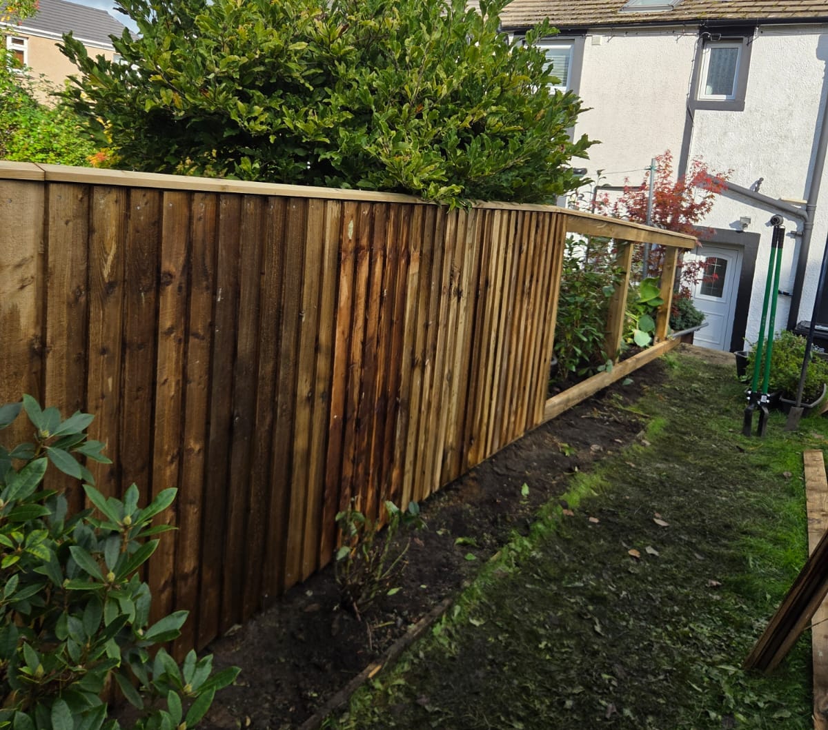 Featheredge boards part fitted along a new timber fence frame in a back garden