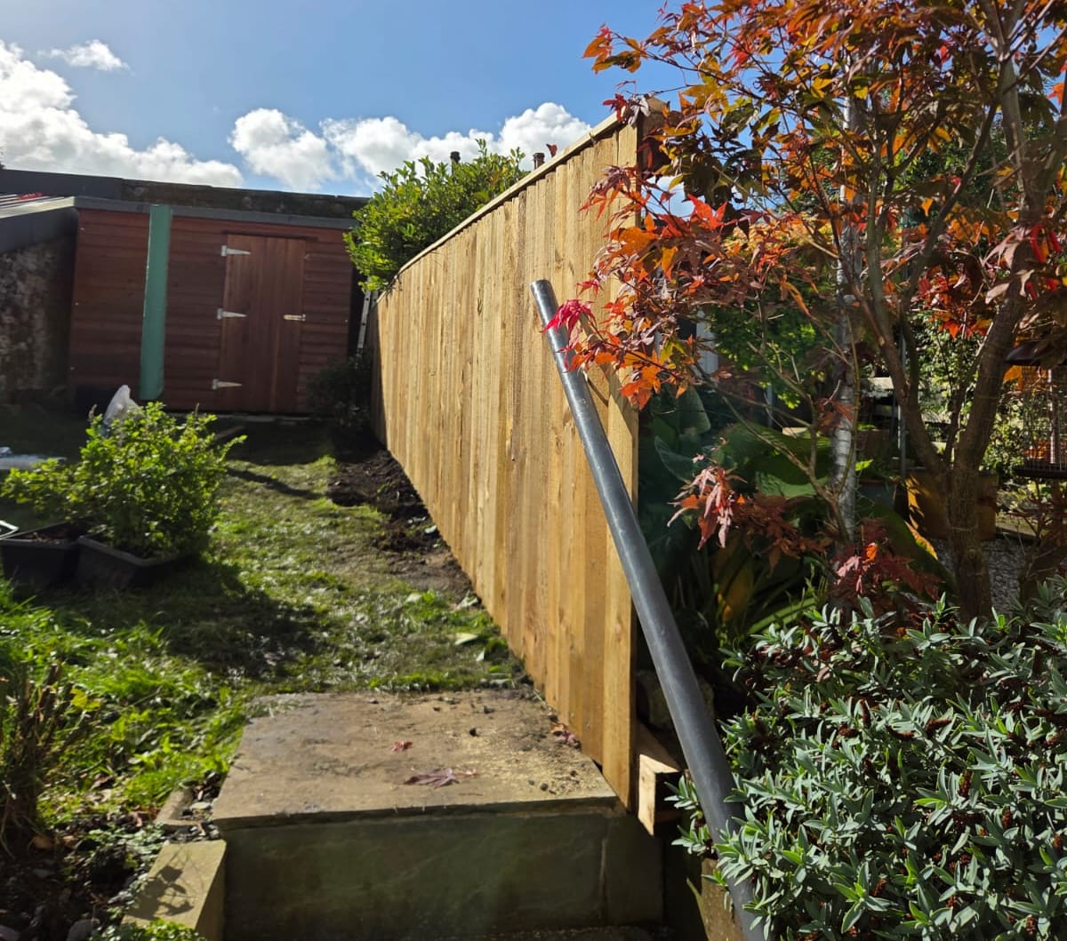 New featheredge fence finishing beside garden steps and a handrail