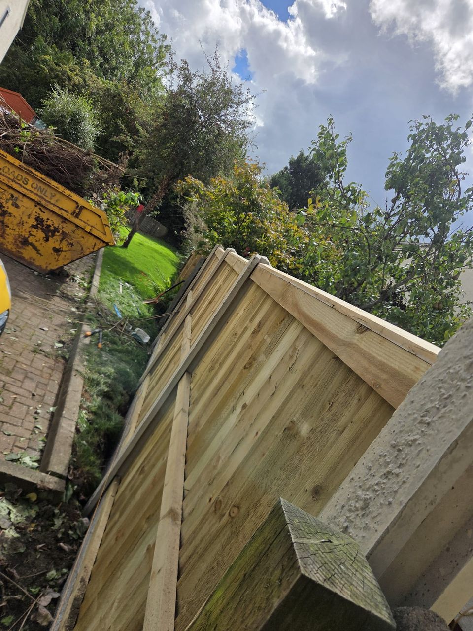 Looking along a newly built fence run with the old fence in a skip behind