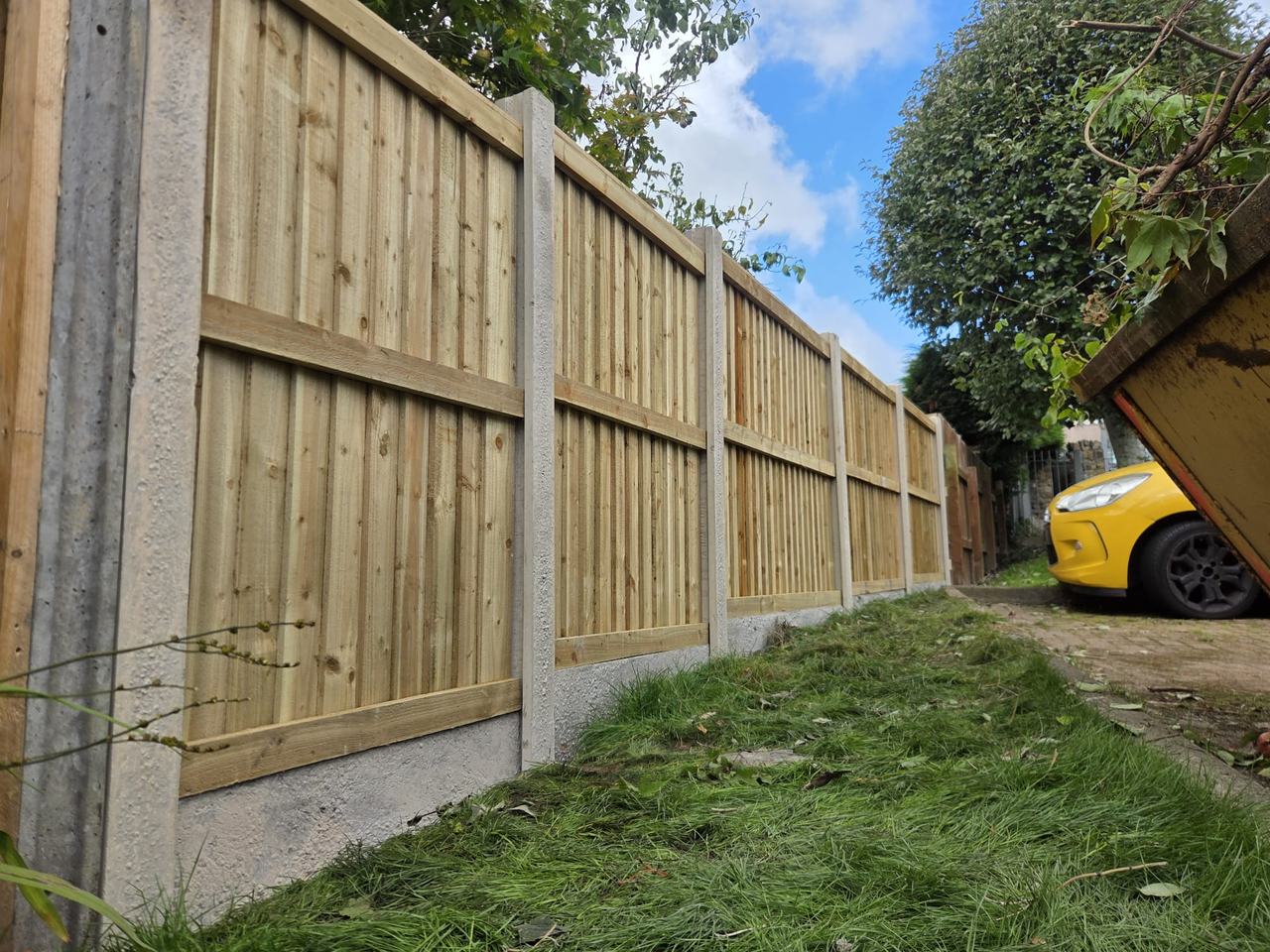 New fence panels in concrete posts and gravel boards along a grass path